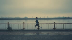 40代男性ランナーが朝の川沿いを一人で走っている様子