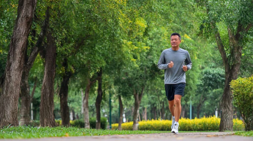 公園でリラックスしたペースで走る40代男性ランナー