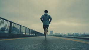 20km走に取り組む40代日本人男性ランナーが河川敷を落ち着いた表情で走っている様子