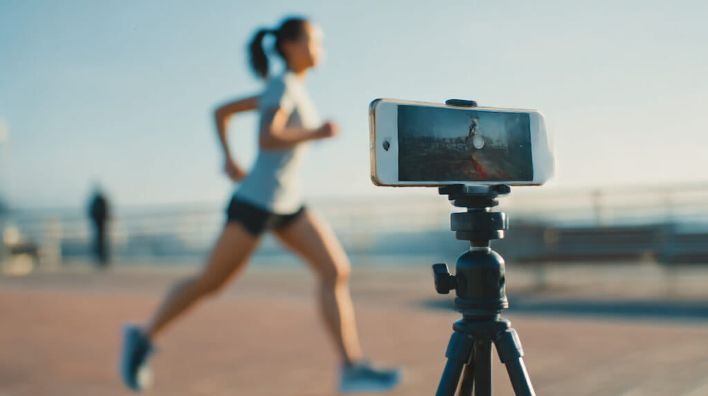 スマートフォンで自分の走りを撮影しフォームを確認する日本人ランナー