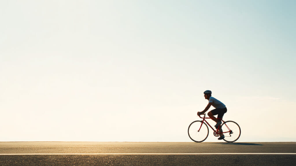 効率よく走れるクロスバイクに乗る日本人サイクリストの走行シーン