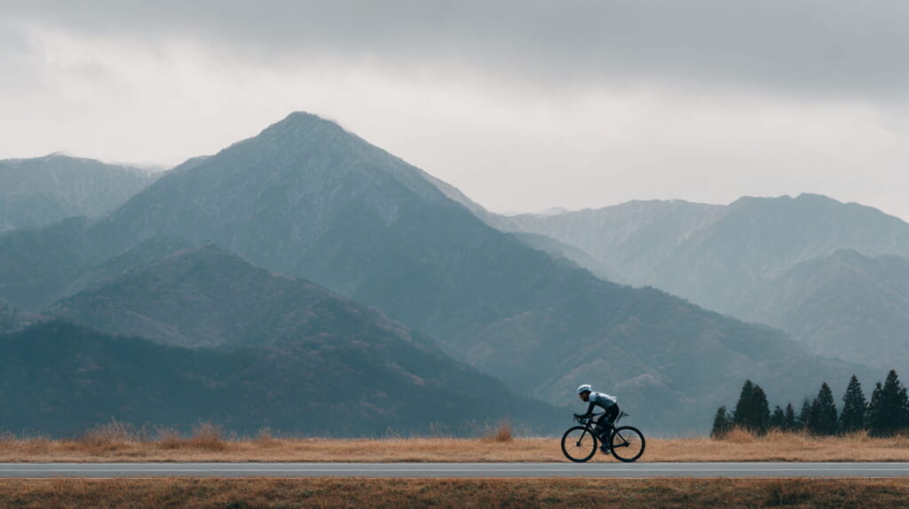 登山後のアクティブリカバリーとしてクロスバイクに乗る日本人男性アスリート