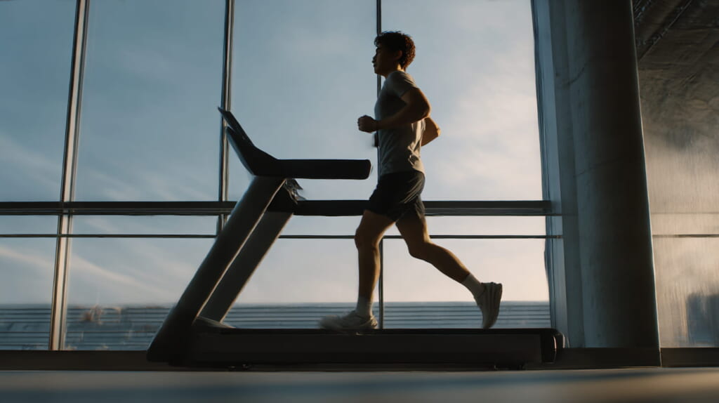 ジムで傾斜をつけたランニングマシンを早歩きする40代の日本人ランナー