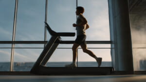 ジムで傾斜をつけたランニングマシンを早歩きする40代の日本人ランナー